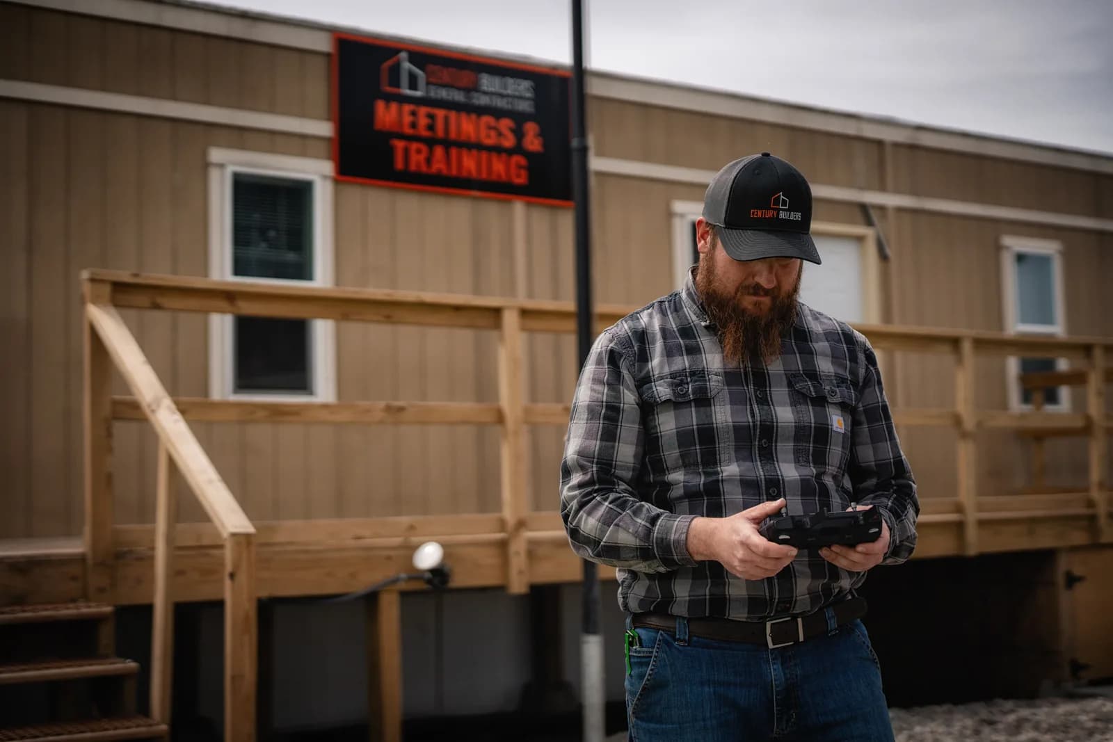 Century Builders team member with a drone controller outside the Meetings & Training field office