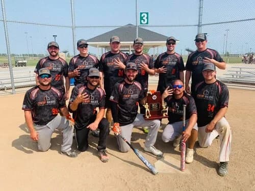 The Century Builders men's softball team posing with a championship trophy on the field