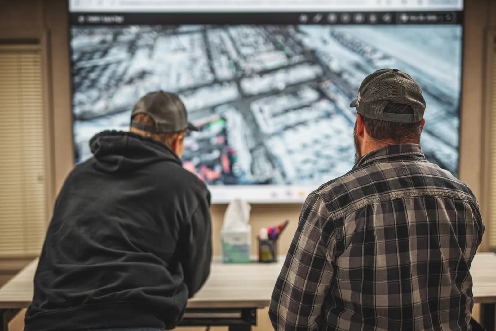 Two team members reviewing an aerial site map on a large display